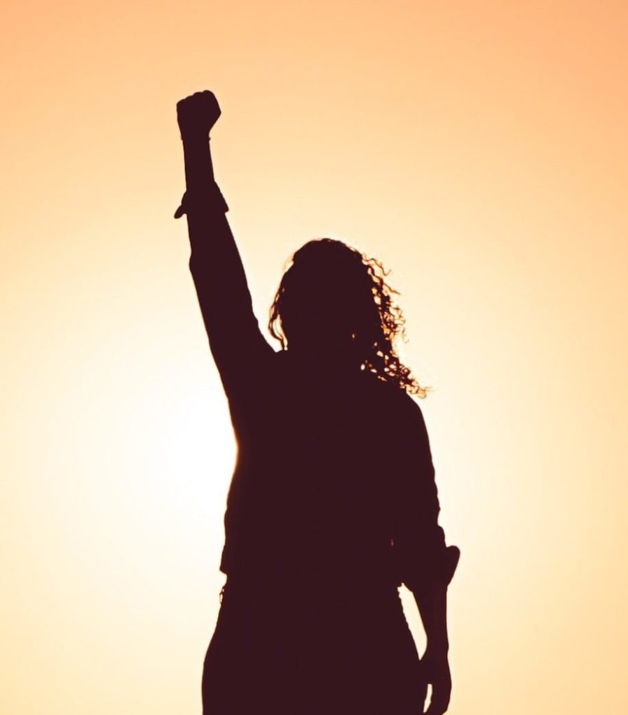 Woman in silhouette with fist clenched and arm raised