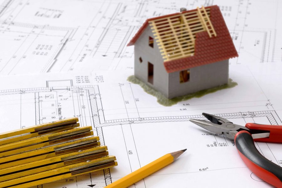 Partially constructed model house sitting on blueprint