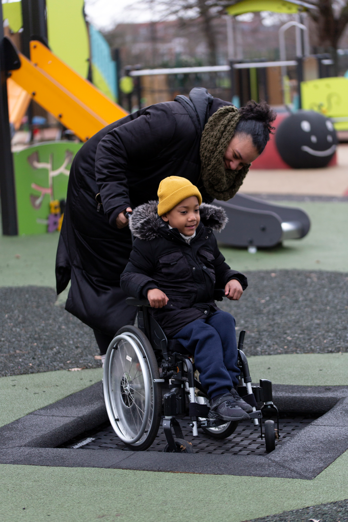 Parent with a child in a wheelchair at an accessible playground