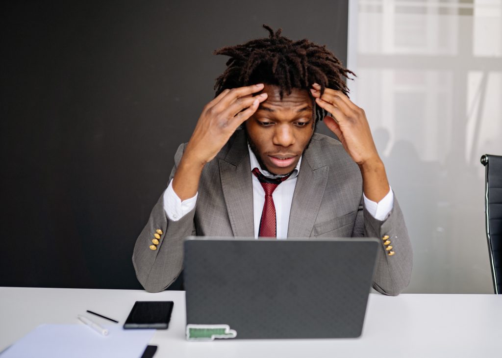 Frustrated man looking at his laptop and holding his head in his hands