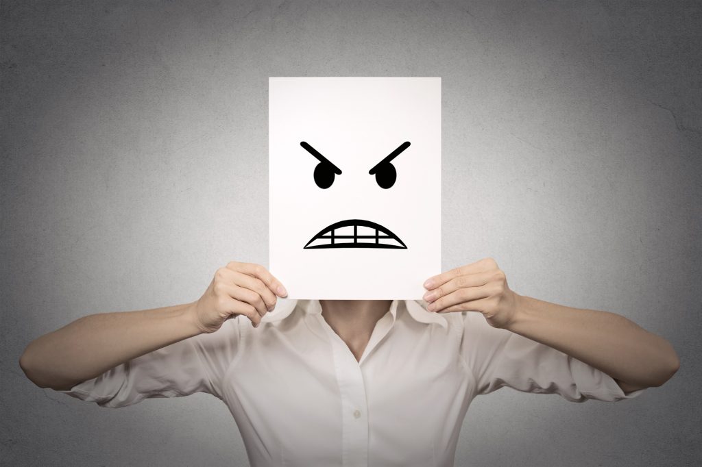 Woman covering her face with angry mask